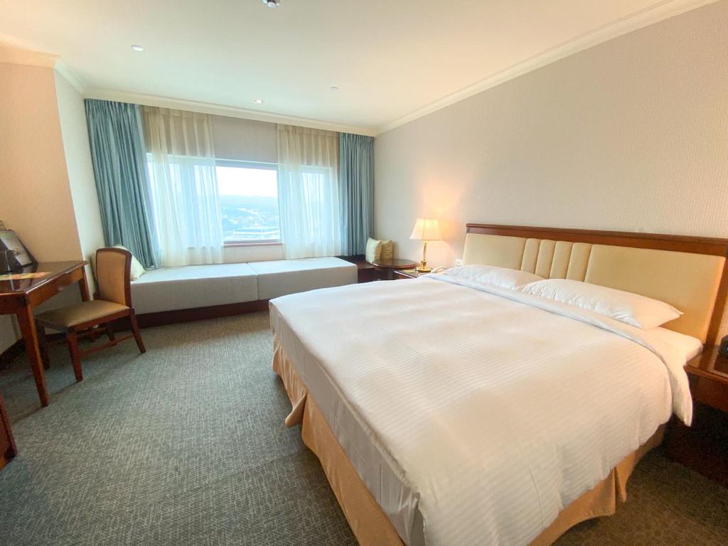 a hotel room with a large bed and a window at Evergreen Laurel Hotel - Keelung in Keelung