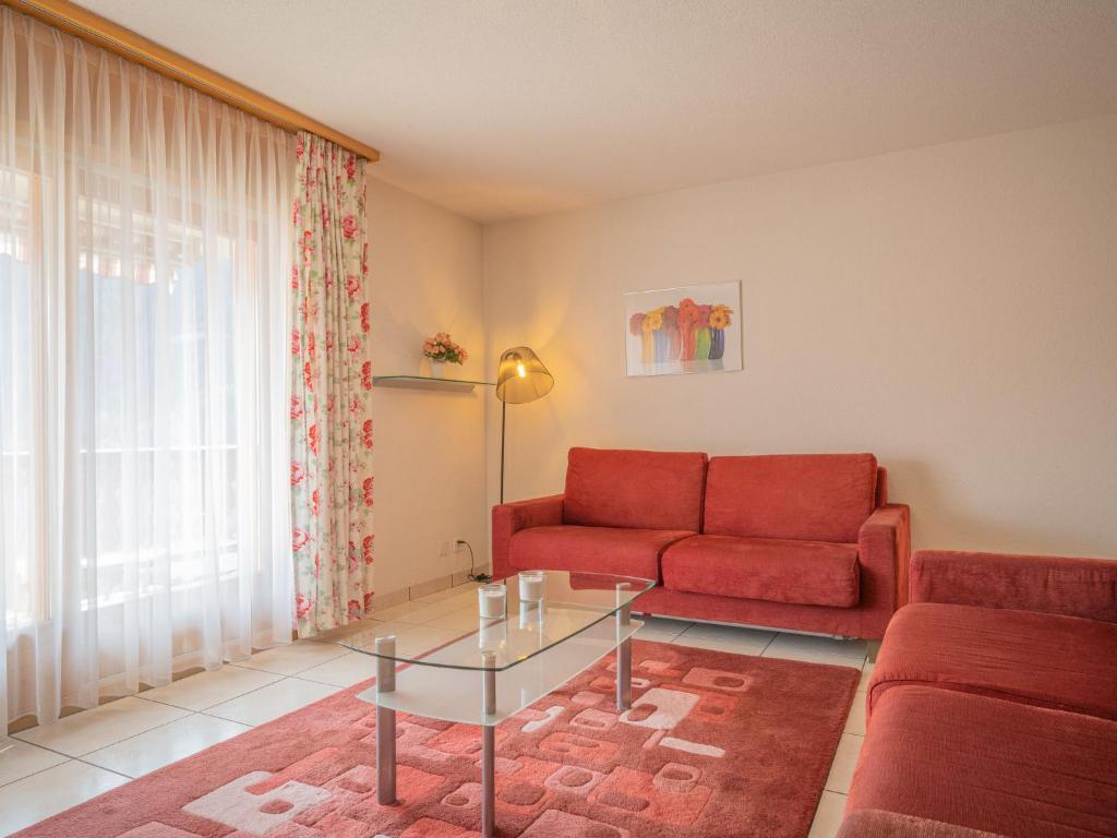 uma sala de estar com um sofá vermelho e uma mesa de vidro em Apartment La Réze No 5 by Interhome em Ovronnaz