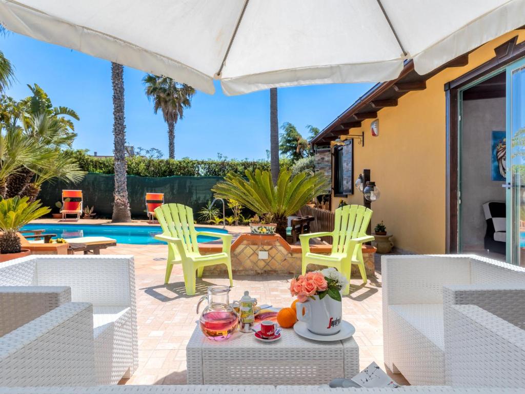 een patio met een tafel en stoelen en een zwembad bij Villa Albert by Interhome in San Leone
