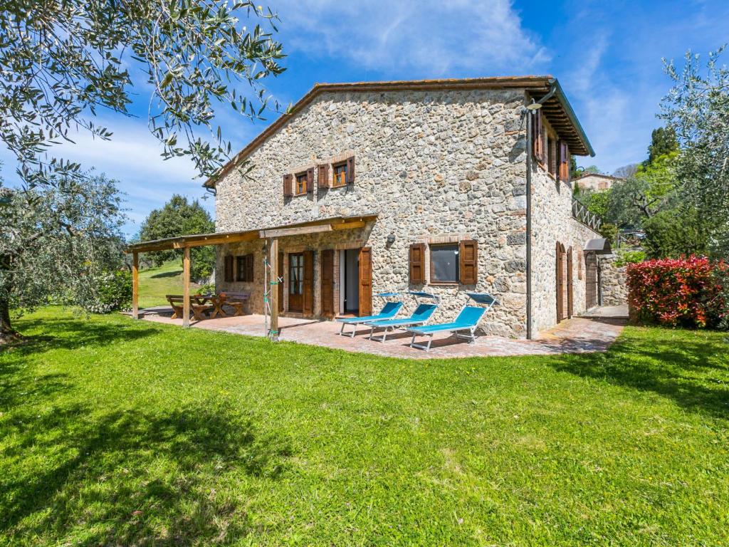 kamienny dom z niebieskimi krzesłami na dziedzińcu w obiekcie Holiday Home Il Fienile by Interhome w mieście Lucciana