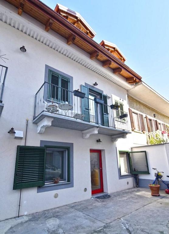 a white house with a balcony and a red door at iL GeLsoMiNo in Brandizzo