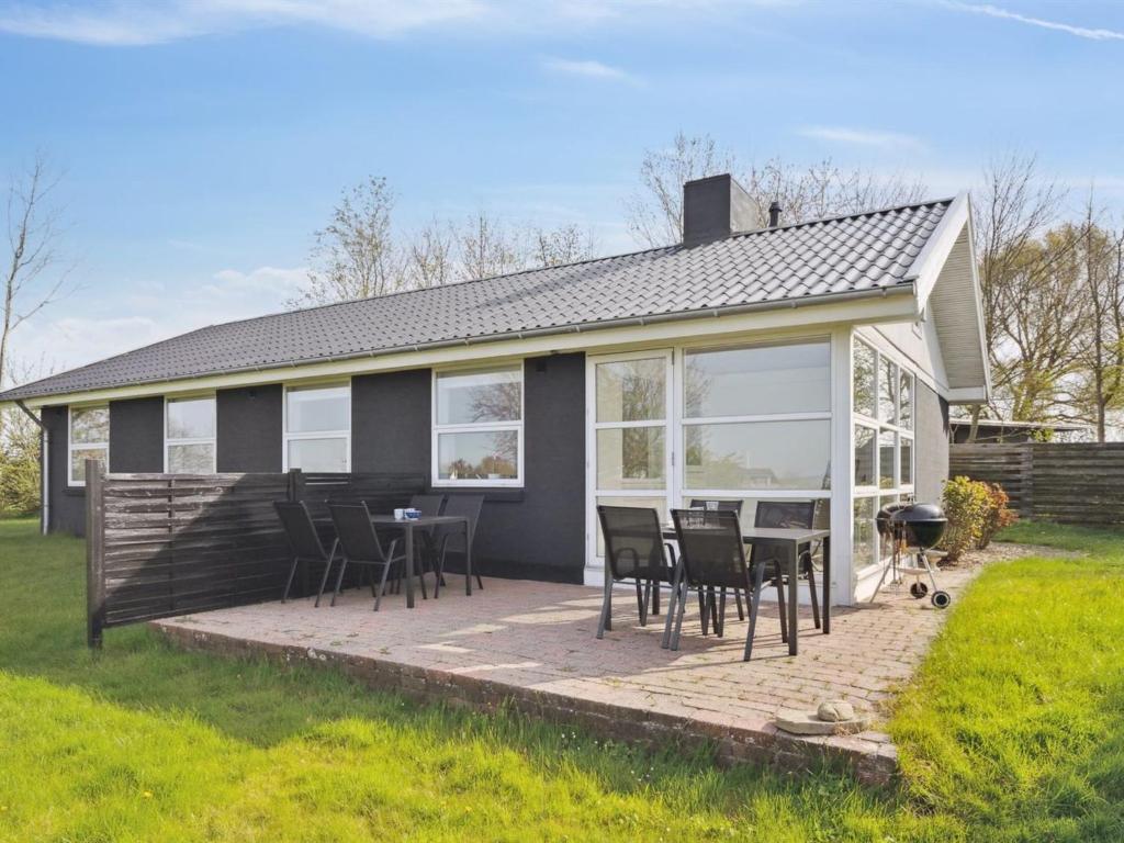a house with a deck with chairs and a grill at Holiday Home Susia - 200m from the sea in Funen by Interhome in Middelfart