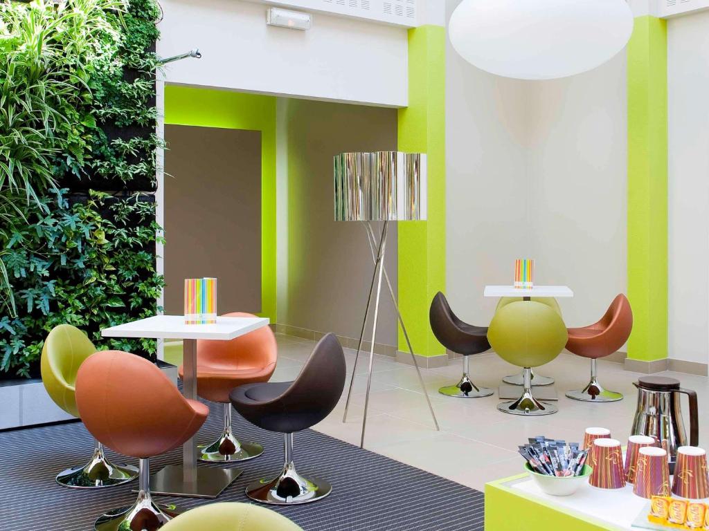 Cette chambre est dotée de chaises, de tables et d'un mur vert. dans l'établissement ibis Styles Bordeaux Aéroport, à Mérignac