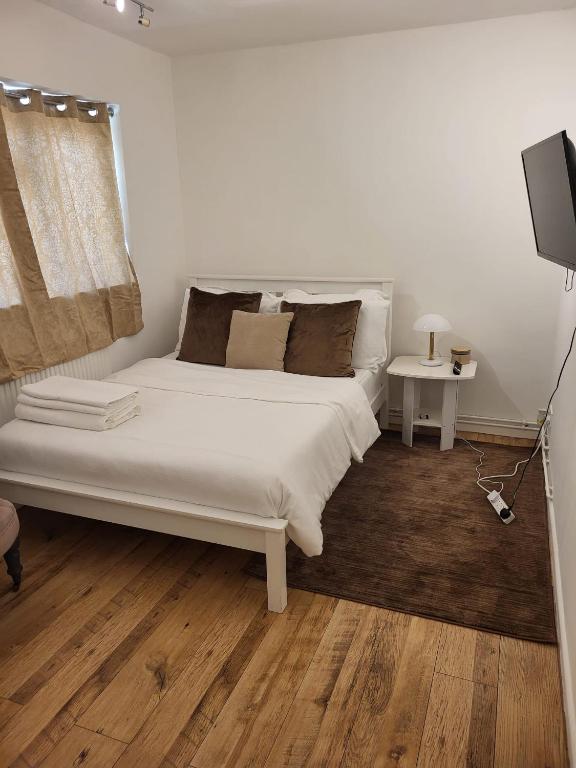 Schlafzimmer mit einem weißen Bett und einem TV in der Unterkunft Quality space in Havering atte Bower