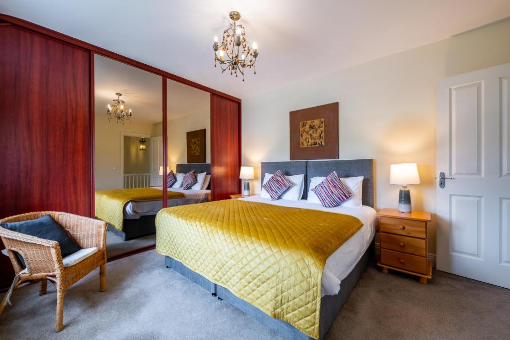 a bedroom with two beds and a chair and a mirror at Foleys Ardmullen Townhouses in Kenmare