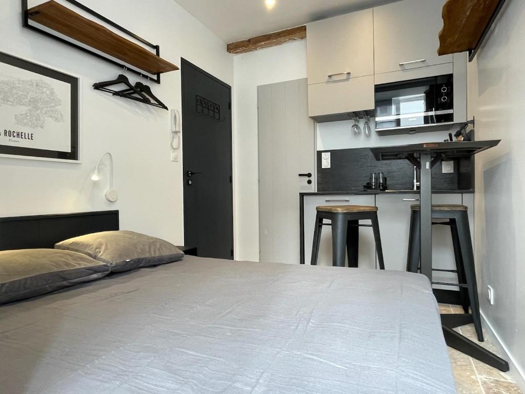 une chambre avec un grand lit et une cuisine dans l'établissement Petite chambre aménagée avec cuisine St Louis 3, à La Rochelle