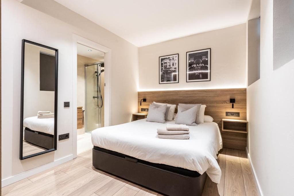 ein Schlafzimmer mit einem großen Bett und einem Spiegel in der Unterkunft Exclusive Apartments Barcelona 4 personas G Humet in Terrassa
