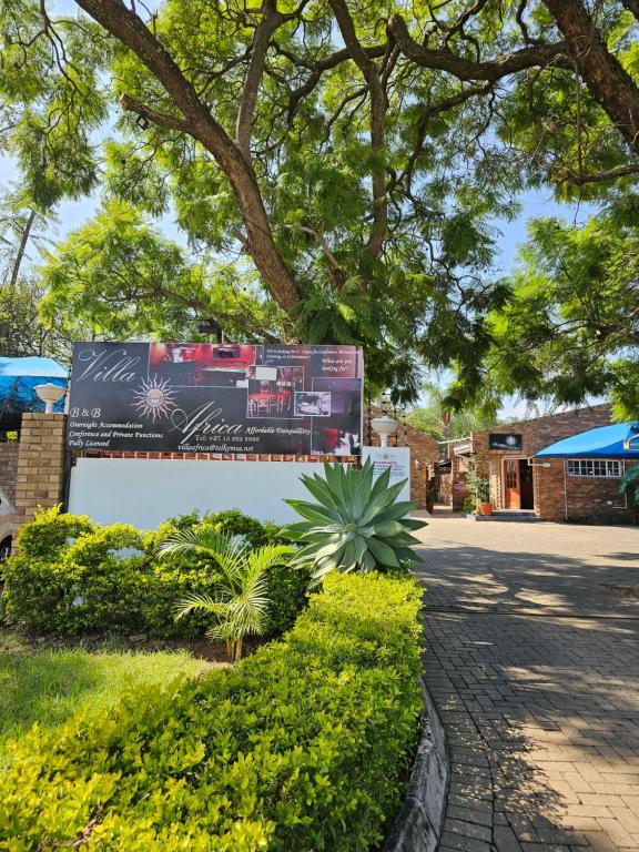 un panneau dans un parc planté d'arbres et de plantes dans l'établissement Motel Villa Africa, à Polokwane