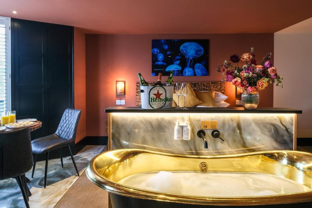 Craig Walk Suite في باونيس أون وينديرمير: حوض استحمام ذهبي في غرفة مع طاولة