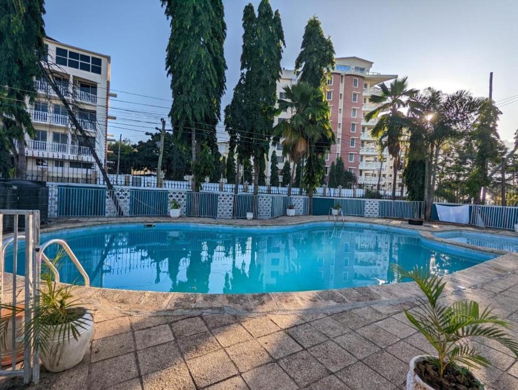 una grande piscina blu con alberi e edifici di Gallivanters Hostel a Dar es Salaam