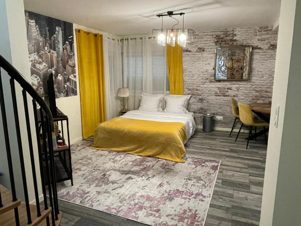 1 dormitorio con cama, mesa y cortinas amarillas en Lodgespa : Maison Rose, en Hésingue