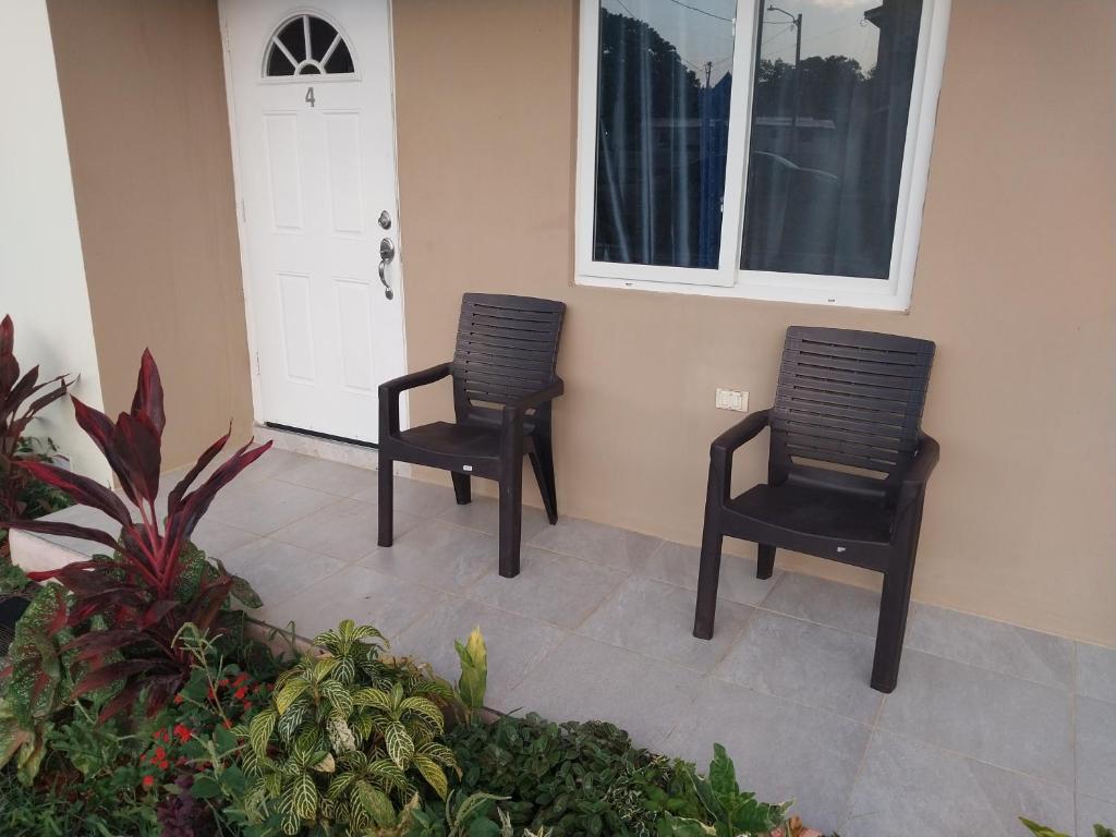 deux chaises noires assises devant une porte dans l'établissement Simpson's residence, à Lucea
