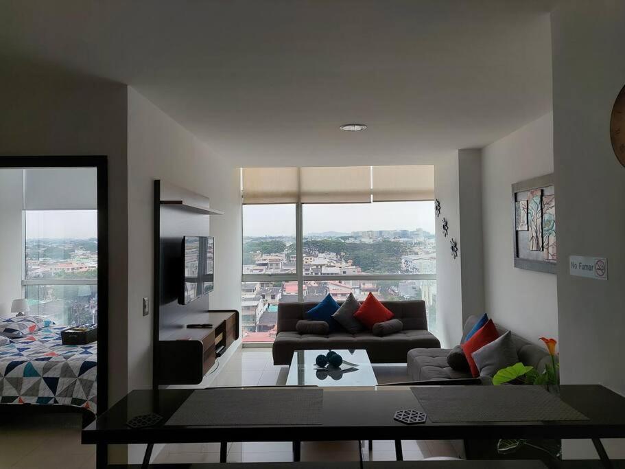 sala de estar con sofá y ventana grande en ZAFIRO SUITE CON VISTA CIUDAD/PISCINA/GYM/ PARQUEO, en Guayaquil