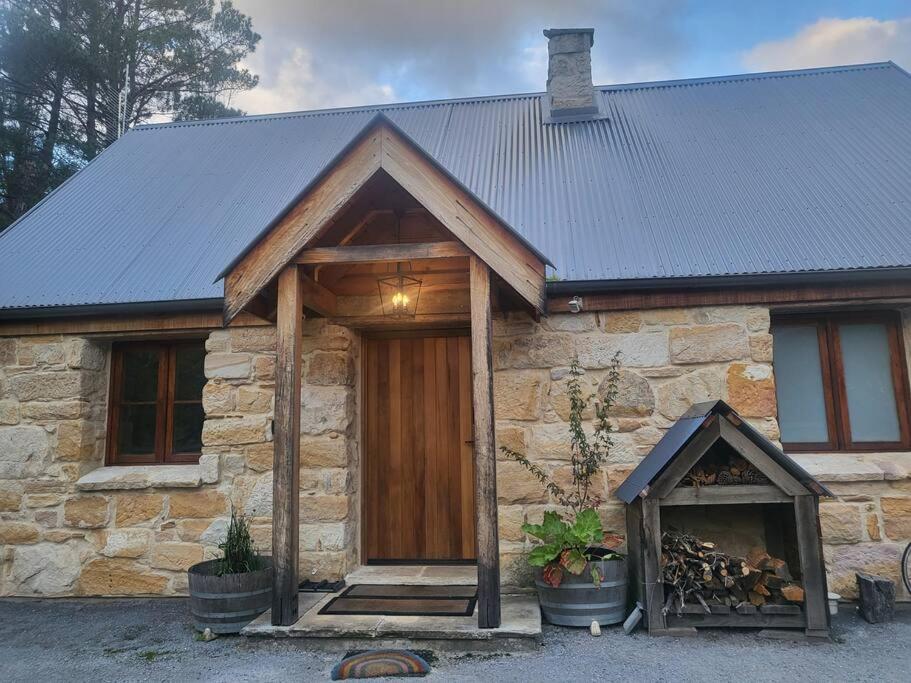 a stone house with a wooden door and a fireplace at The Cottage Burradoo in Burradoo