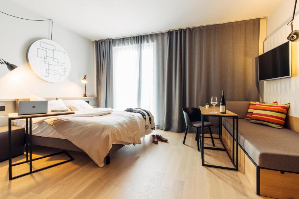 um quarto de hotel com uma cama, uma secretária e uma mesa em harry's home Zürich-Limmattal em Spreitenbach