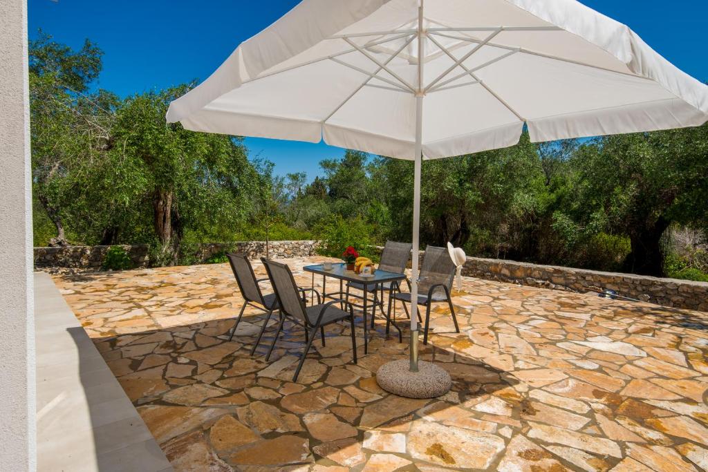 a table with an umbrella on a stone patio at Kabos house in Mastorátika