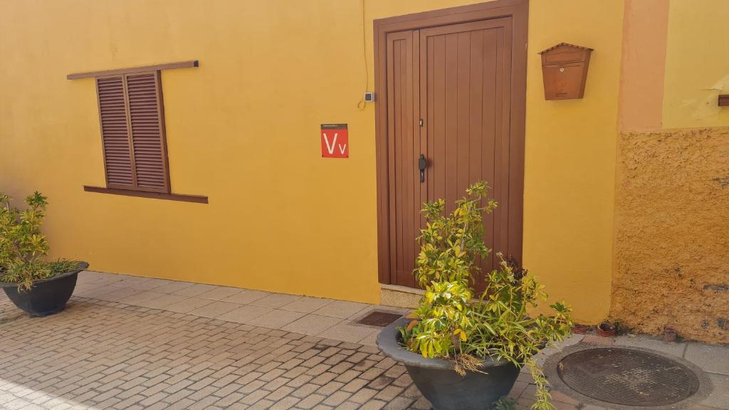 un bâtiment jaune avec une porte munie d'un panneau de signalisation. dans l'établissement Casa Mamatita, à Agüimes