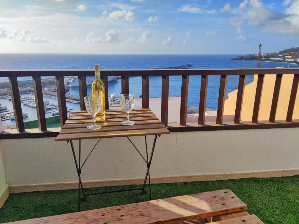 uma mesa com uma garrafa de vinho e copos numa varanda em Vivienda Balcón al amanecer em Santa Cruz de la Palma