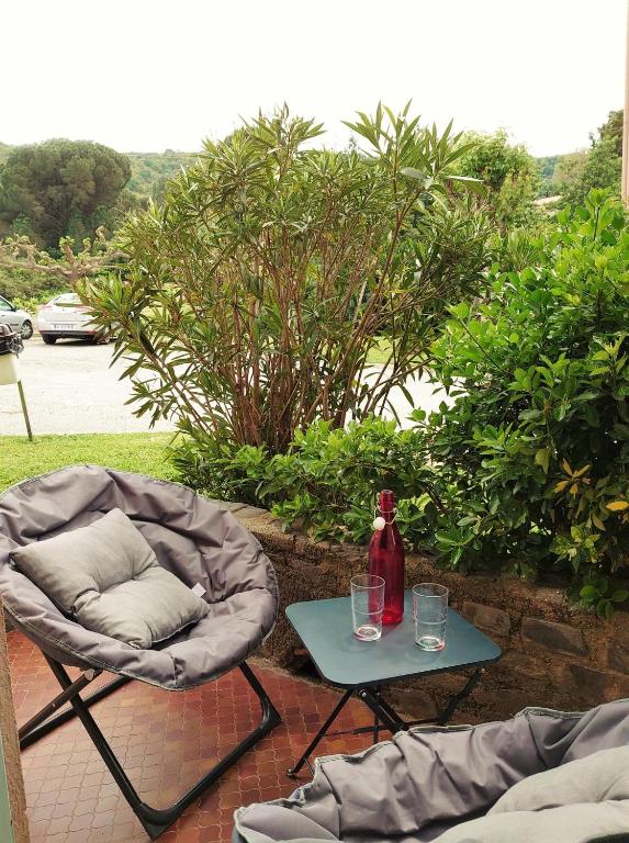 une chaise et une table avec une bouteille et des verres dans l'établissement 4PA76 Appartement avec piscine et parking, à Collioure