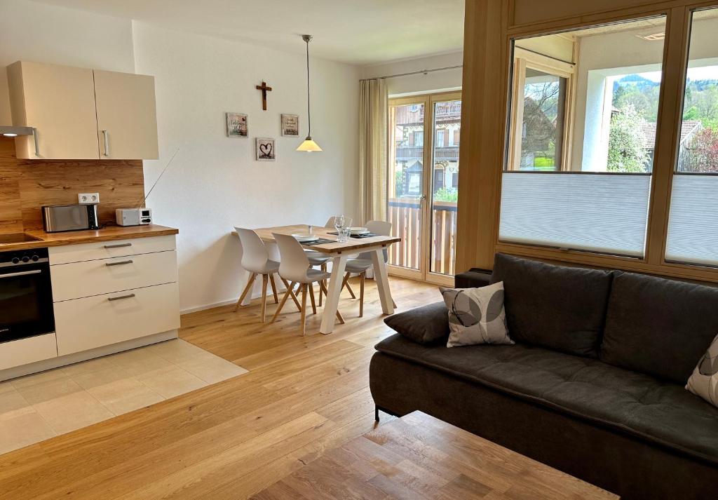 a living room with a couch and a kitchen with a table at Apartment Breitensteinblick - wandern, radeln und Mehr in Fischbachau