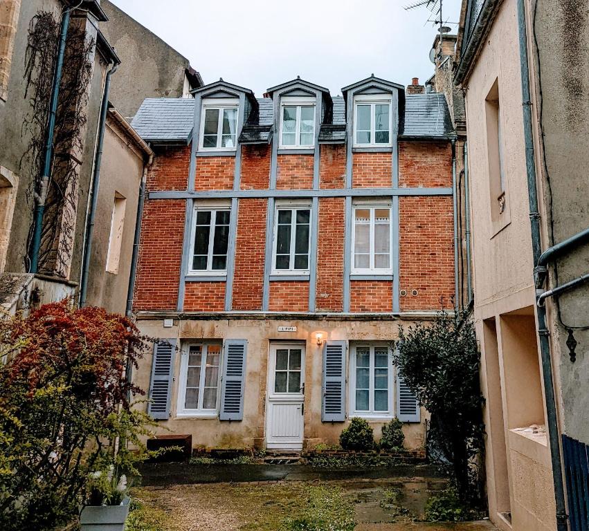 un gran edificio de ladrillo con ventanas y persianas blancas en Charmante maison front de mer et centre ville, en Luc-sur-Mer