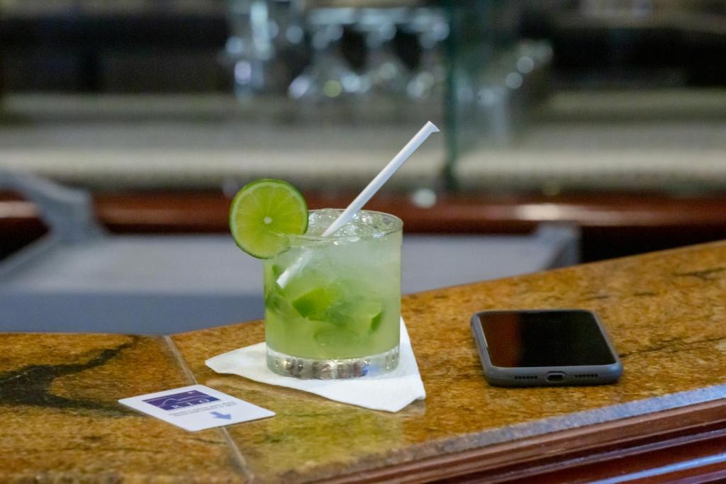 a drink with a lime on a table with a cell phone at Rio Aeroporto Hotel Galeão in Rio de Janeiro