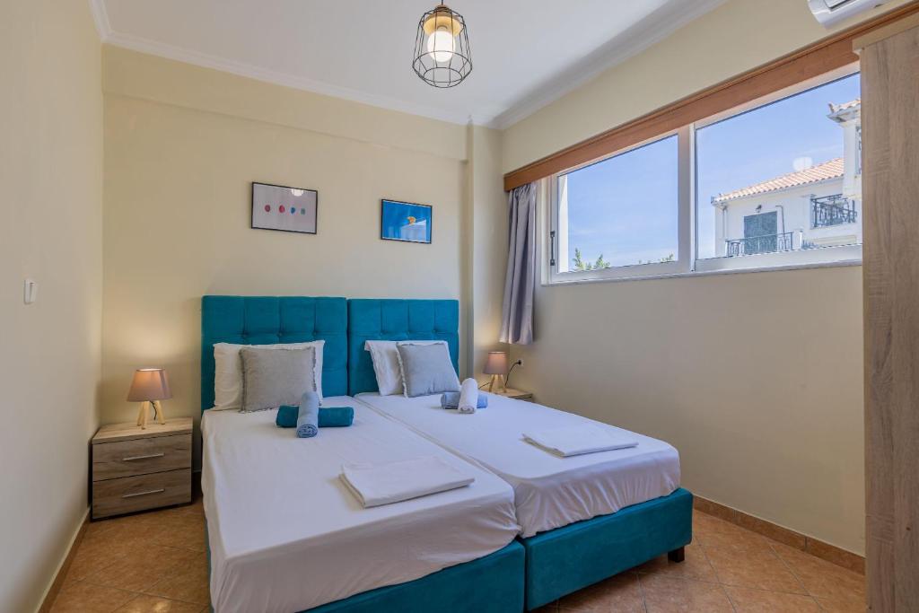 a bedroom with a blue bed and a large window at Scarlett City Apartment in Zakynthos Town