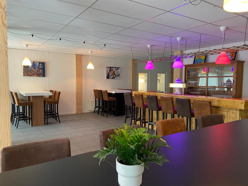 un restaurant avec des tables, des chaises et des lumières roses dans l'établissement Landgoed Leudal, à Haelen
