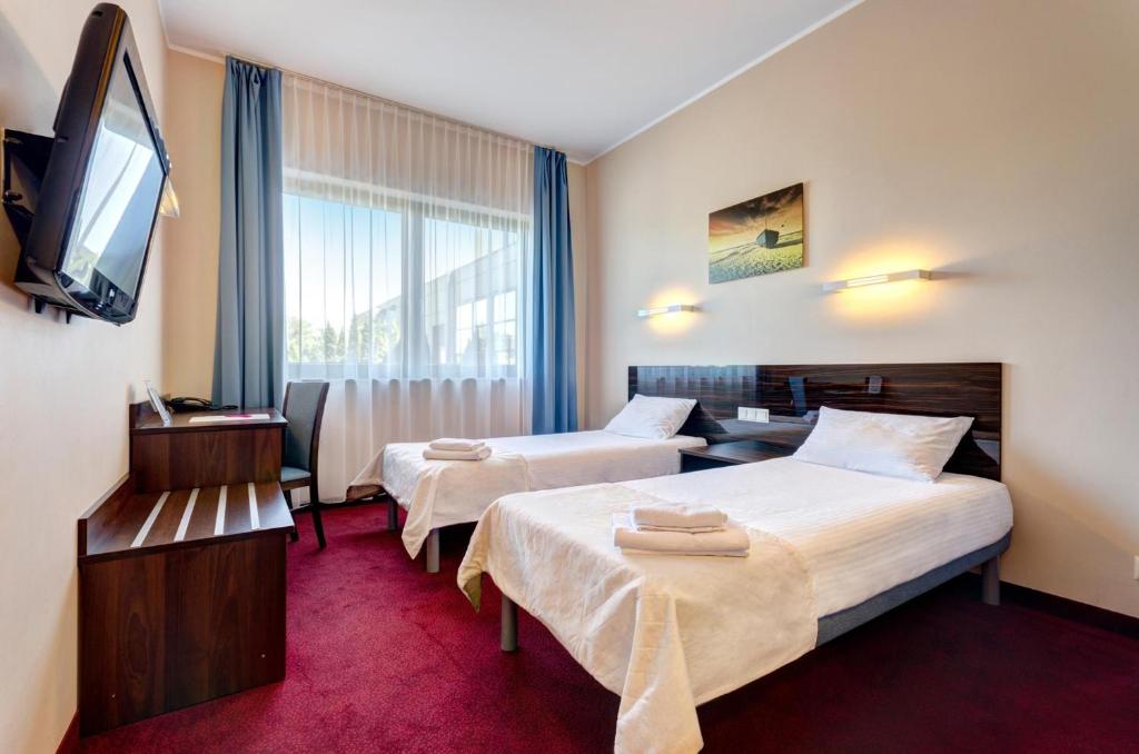 a hotel room with two beds and a flat screen tv at Focus Hotel Gdańsk in Gdańsk