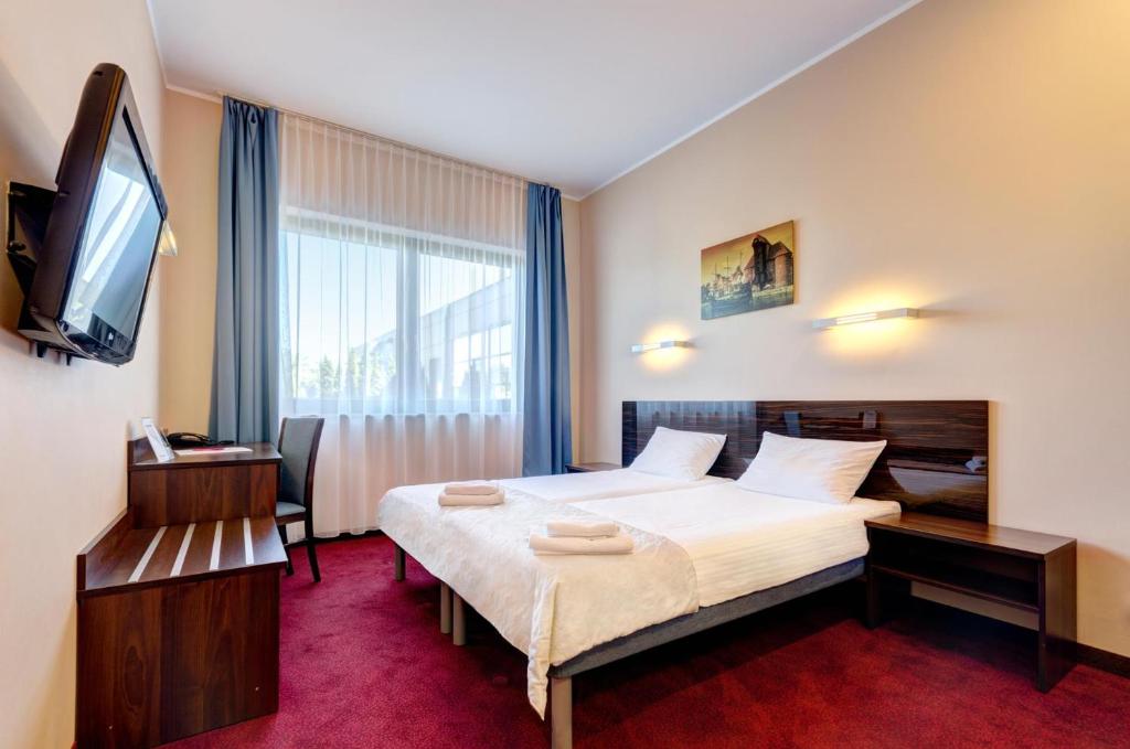 a hotel room with a bed and a television at Focus Hotel Gdańsk in Gdańsk