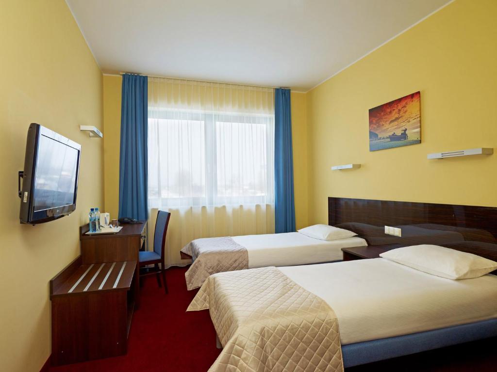 a hotel room with two beds and a flat screen tv at Focus Hotel Gdańsk in Gdańsk