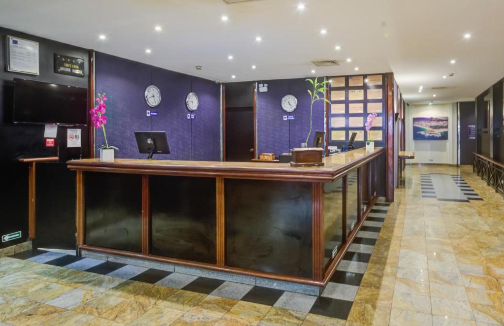 a lobby with a reception desk and clocks on the wall at Rio Aeroporto Hotel Galeão in Rio de Janeiro