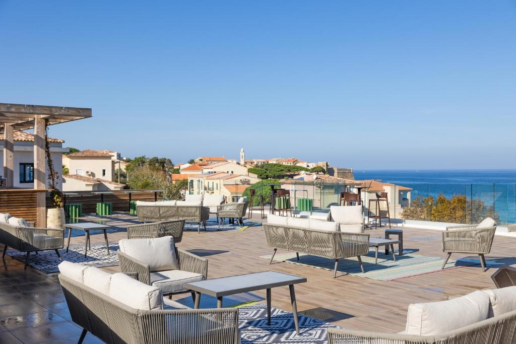 - un ensemble de chaises et de tables sur une terrasse donnant sur l'océan dans l'établissement Eco-Résidence Dolce Paese, à Algajola