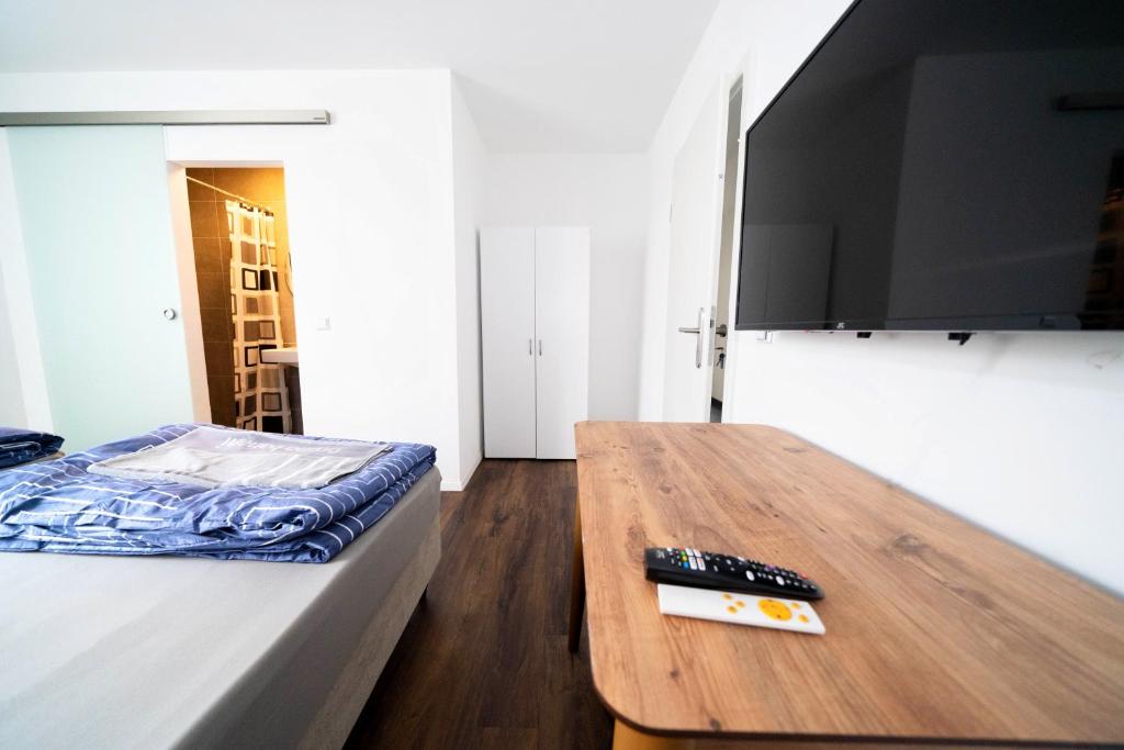 a bedroom with a bed and a wooden table with a tv at Pension Diloyal in Nürtingen