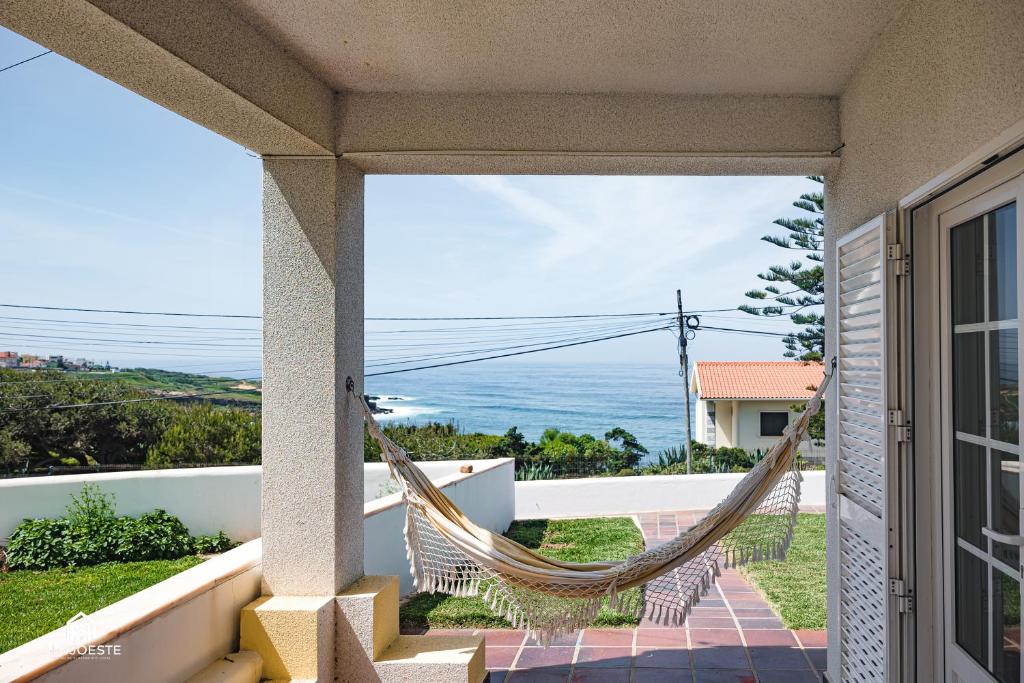 una hamaca en el balcón de una casa con vistas al océano en Villa Castelo de Mar, en Ericeira