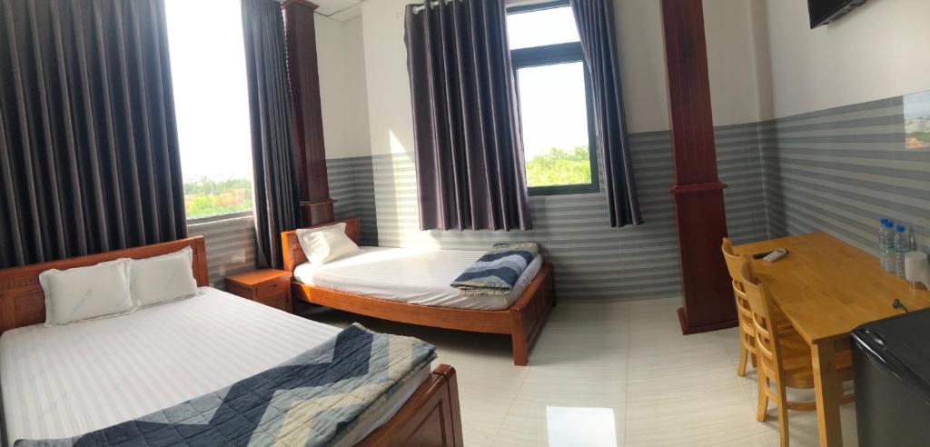 Habitación con 2 camas, escritorio y ventanas. en Hotel Sen Việt Bạc Liêu en Bạc Liêu
