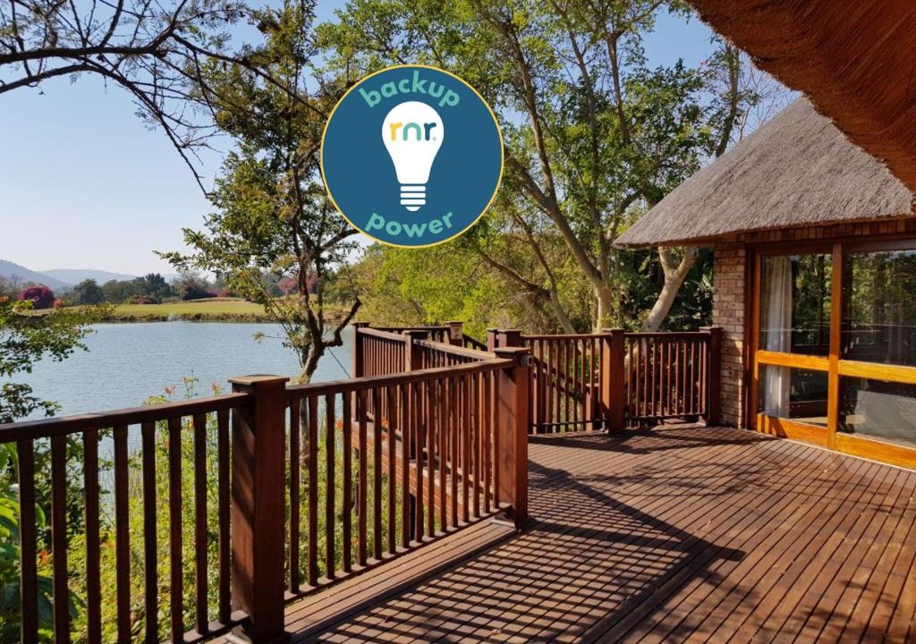 a wooden deck with a light bulb sign next to a lake at Kruger Park Lodge ITR01 3 Bedroom in Hazyview