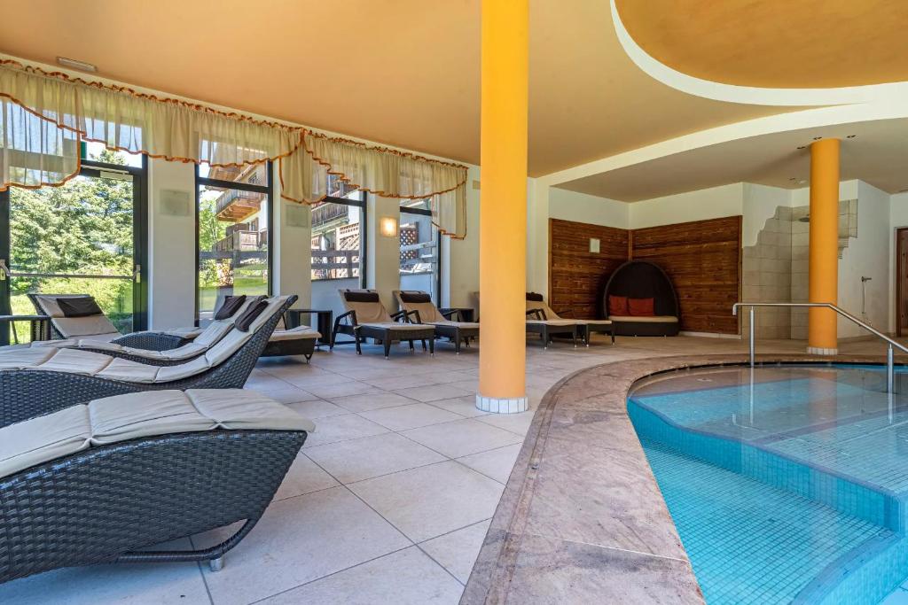 a swimming pool in a hotel with chairs at Ferienparadies Sabina Lärche in Alpe di Siusi