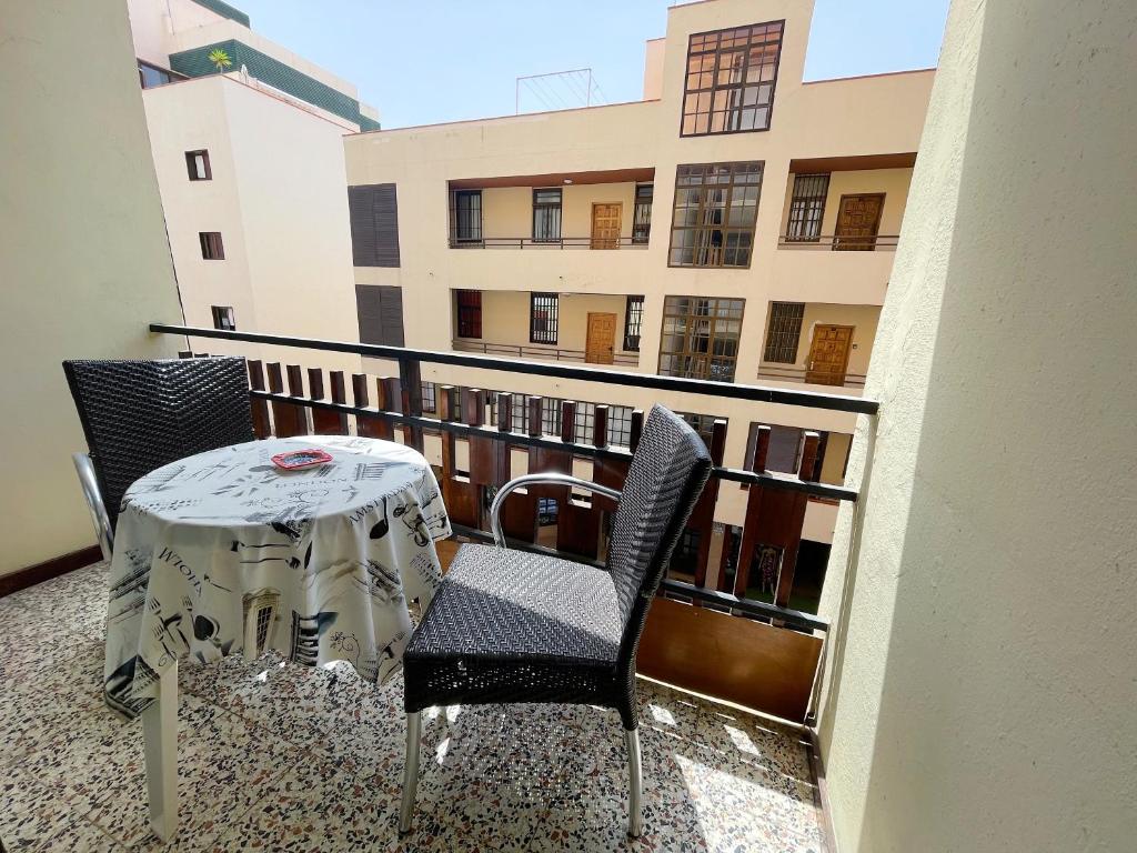 uma mesa e cadeiras numa varanda com um edifício em Apartamento Canarias em Los Cristianos