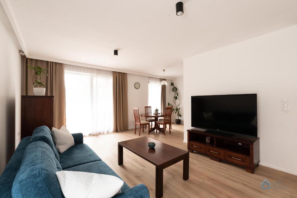sala de estar con sofá azul y TV de pantalla plana en Granero Deluxe by 3City Rentals, en Gdansk