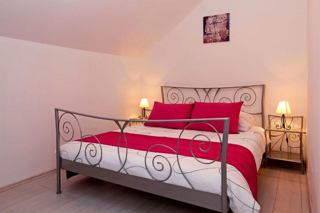 1 dormitorio con 1 cama grande con almohadas rojas en Apartments Park, en Vela Luka