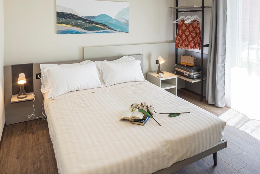 CASCINA SANT'ANTONIO في ألبا: غرفة نوم بسرير عليها كتاب وزهور