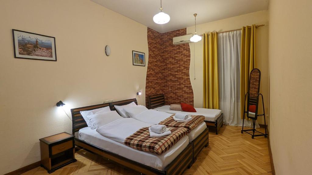 a bedroom with two beds and a brick wall at Guesthouse Kartli in Tbilisi City