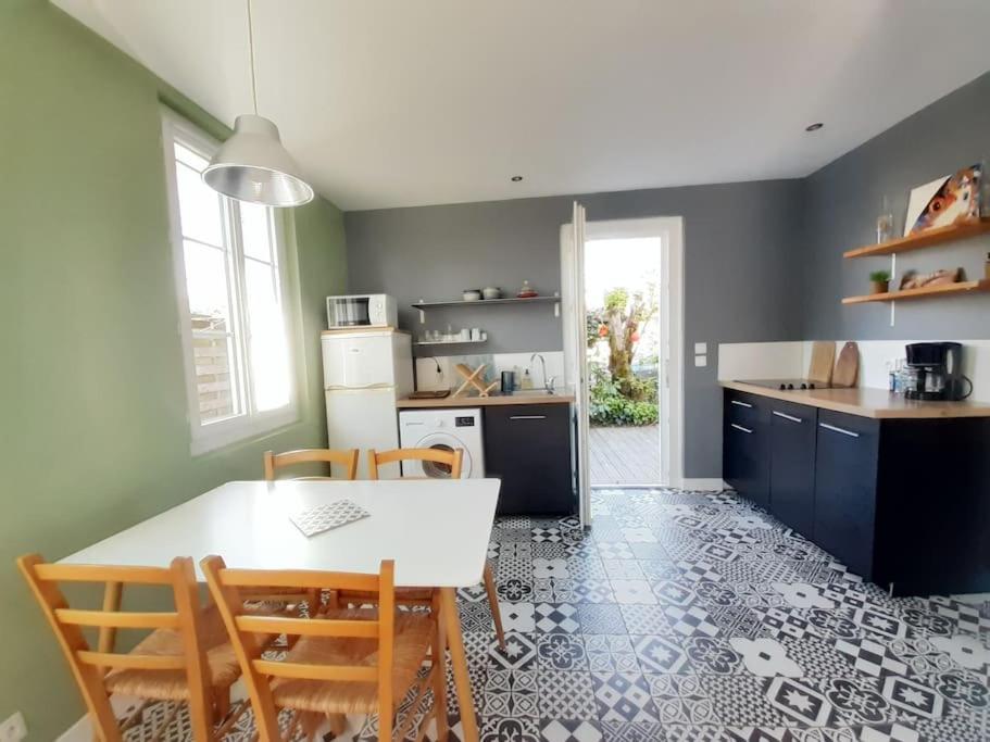 uma cozinha com uma mesa branca e cadeiras num quarto em La cabane du pêcheur proche plage em Arès