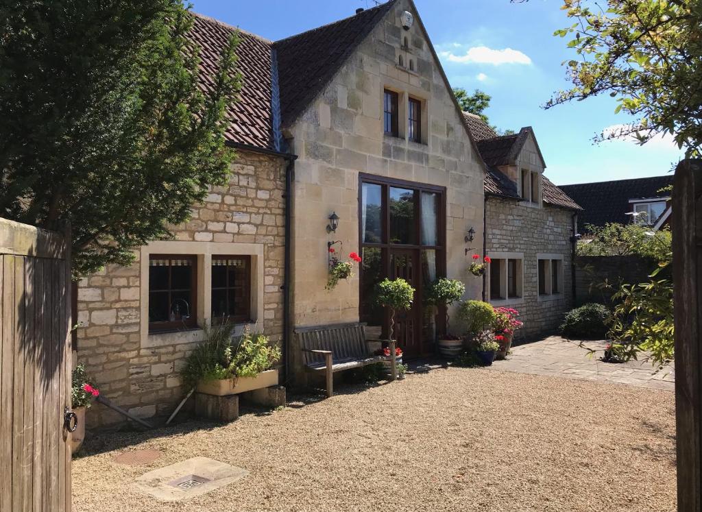 uma casa de pedra com um banco à frente em Converted Coach House Holt, Wiltshire em Holt