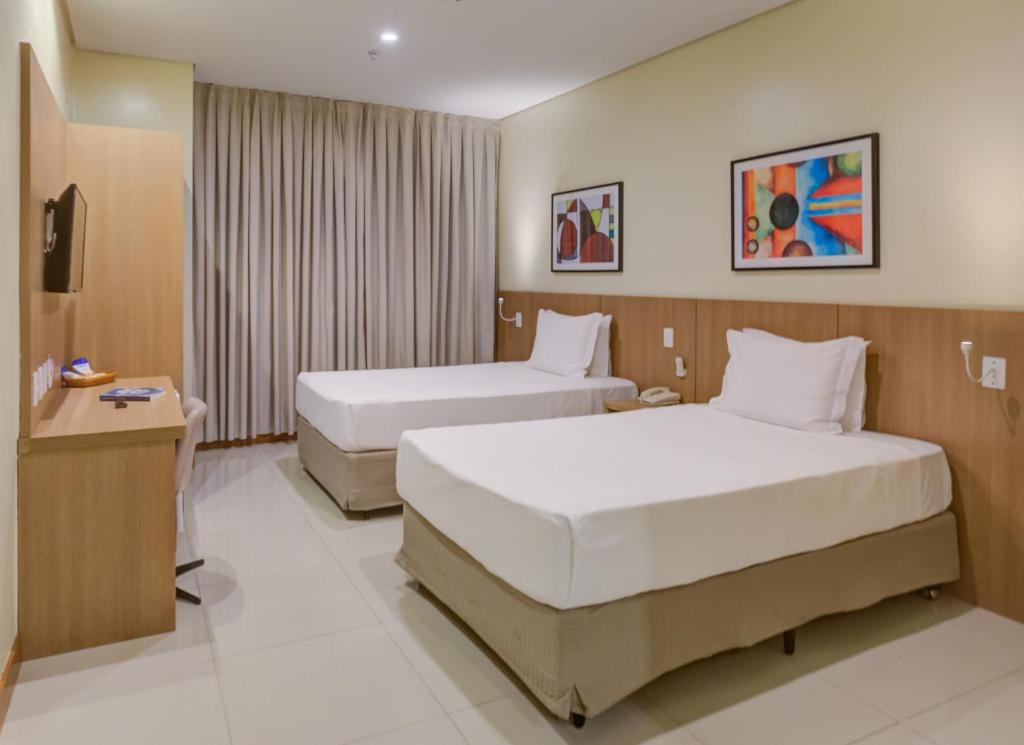 a hotel room with two beds and a television at Rio Aeroporto Hotel Galeão in Rio de Janeiro
