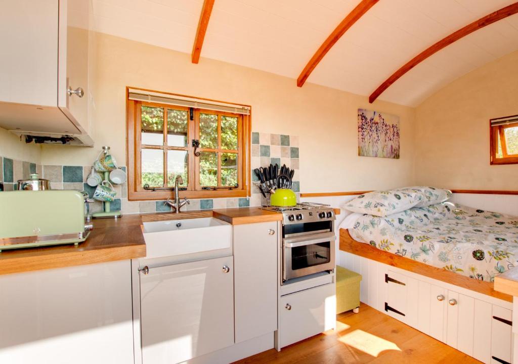 a kitchen with white cabinets and a bed in it at The Cloud in Bampton