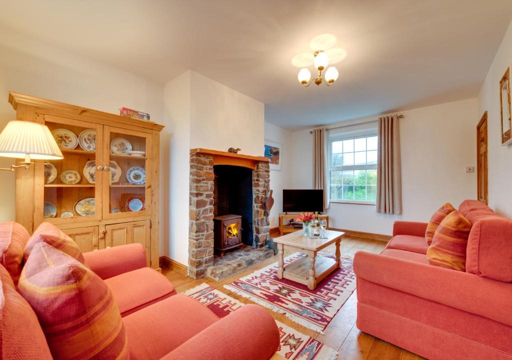 a living room with two red couches and a fireplace at Coastguard Cottage in Blagberry