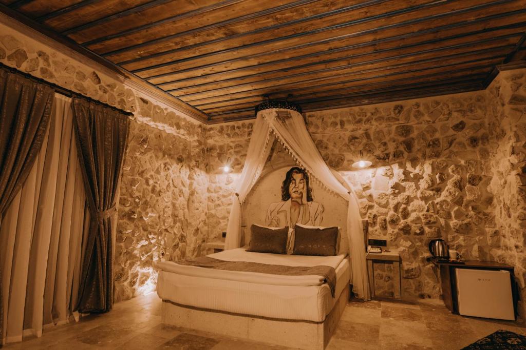 a bedroom with a bed with a portrait of a man at AKRİTİS STONE HOUSE in Urgup