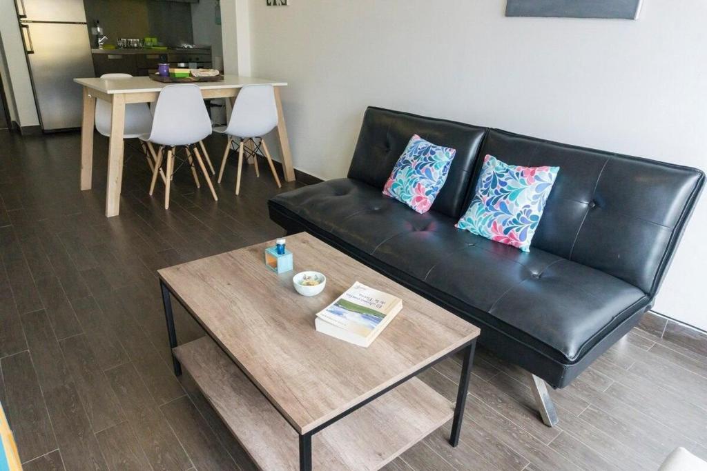 a living room with a black leather couch and a table at Gente del Sur - Rivadavia in Ushuaia